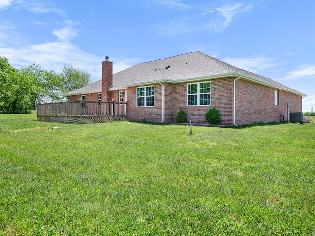 8863 Serene Acres Ln, Rogersville, MO 65742 - rear view of house featuring central AC unit, a deck, a lawn, brick siding, and a chimney