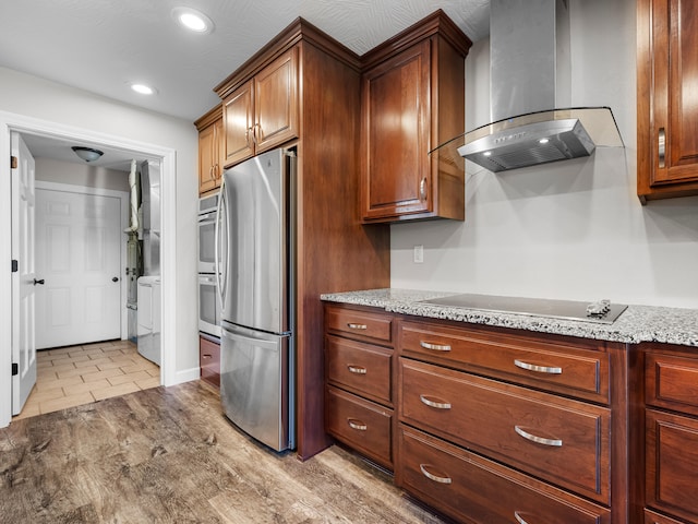 8863 Serene Acres Ln, Rogersville, MO 65742 - kitchen featuring wall chimney exhaust hood, freestanding refrigerator, light stone counters, black electric cooktop, and recessed lighting