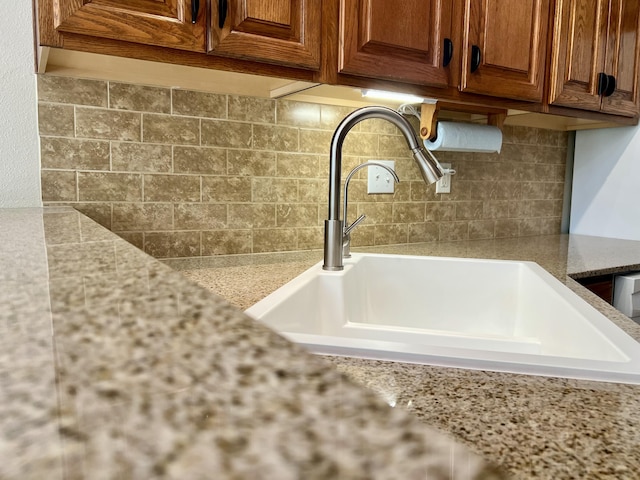 1207 Ledgestone Cir, Branson West, MO 65737 - detailed view of a sink, tasteful backsplash, light stone counters, and brown cabinetry