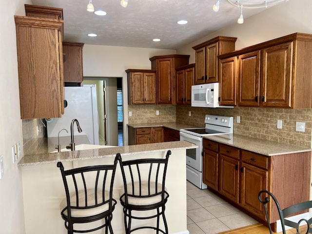 1207 Ledgestone Cir, Branson West, MO 65737 - kitchen featuring white appliances, a peninsula, a breakfast bar area, tasteful backsplash, and light tile patterned floors