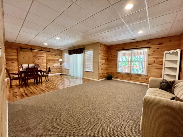 1207 Ledgestone Cir, Branson West, MO 65737 - living room featuring a barn door, wooden walls, recessed lighting, wood finished floors, and carpet