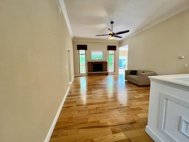 1207 Ledgestone Cir, Branson West, MO 65737 - living area featuring ornamental molding, light wood-style floors, baseboards, ceiling fan, and a fireplace with raised hearth