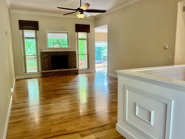 1207 Ledgestone Cir, Branson West, MO 65737 - unfurnished living room featuring crown molding, light wood-type flooring, ceiling fan, baseboards, and a fireplace with raised hearth