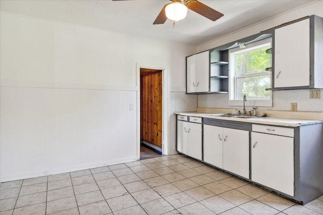 1823 W Olive St, Springfield, MO 65802 - kitchen featuring light countertops, a sink, open shelves, a wainscoted wall, and white cabinets