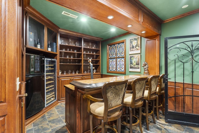 5575 S Castlebay Dr, Springfield, MO 65809 - indoor bar featuring ornamental molding, refrigerator, beverage cooler, dark stone finish flooring, and recessed lighting