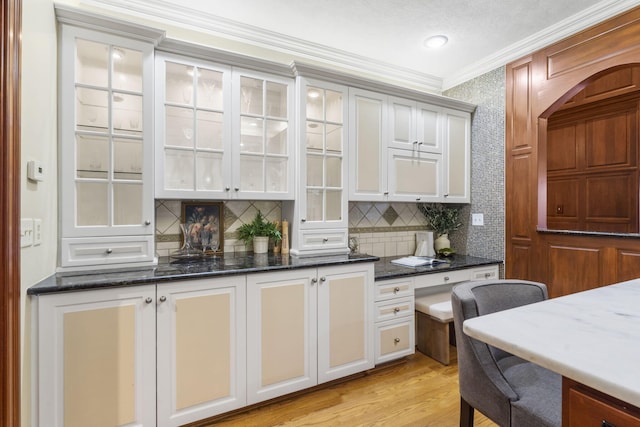 5575 S Castlebay Dr, Springfield, MO 65809 - kitchen featuring ornamental molding, tasteful backsplash, dark stone countertops, glass insert cabinets, and light wood-style flooring