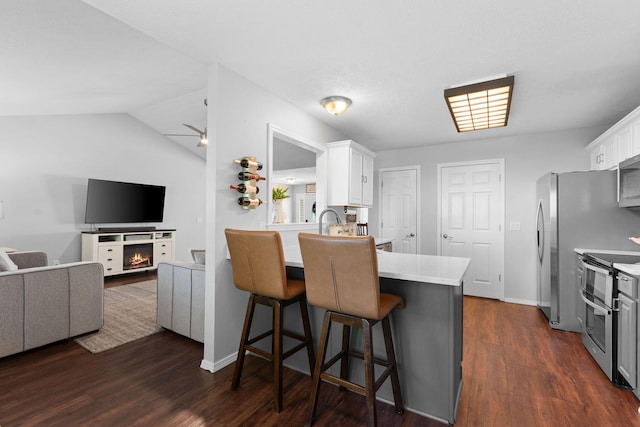 181 Rosewood Ln, Branson, MO 65616 - kitchen featuring appliances with stainless steel finishes, white cabinetry, dark wood-type flooring, light countertops, and a kitchen bar