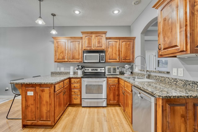 3192 W Melbourne St, Springfield, MO 65810 - kitchen with stainless steel appliances, a sink, a peninsula, light wood finished floors, and light stone counters
