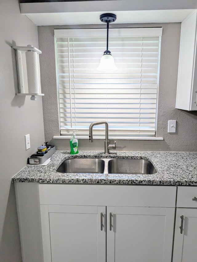 204 E College St, Walnut Grove, MO 65770 - kitchen with a sink, a textured wall, white cabinetry, decorative light fixtures, and light stone countertops