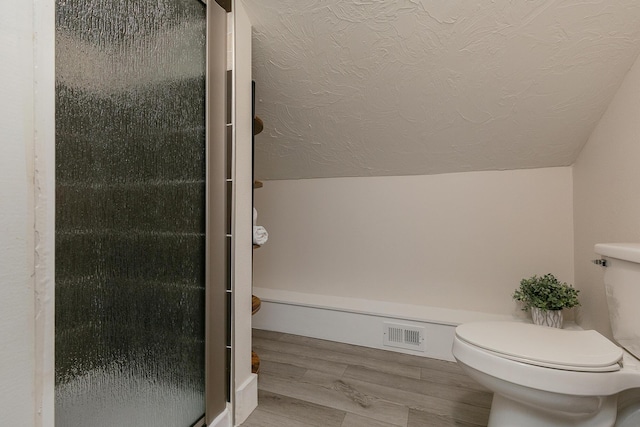 439 Union Chapel Rd, Fordland, MO 65652 - bathroom with toilet, a textured ceiling, vaulted ceiling, a stall shower, and wood finished floors