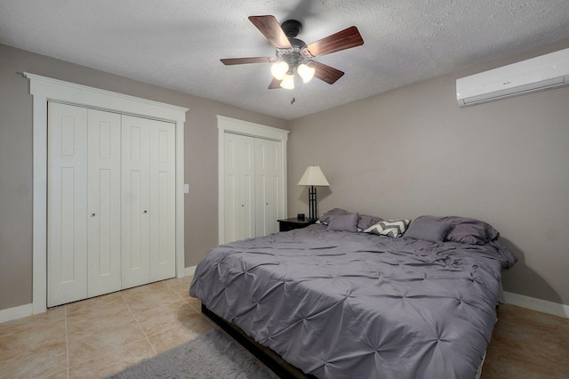 5116 S 165th Rd, Bolivar, MO 65613 - tiled bedroom featuring an AC wall unit, multiple closets, baseboards, a textured ceiling, and a ceiling fan