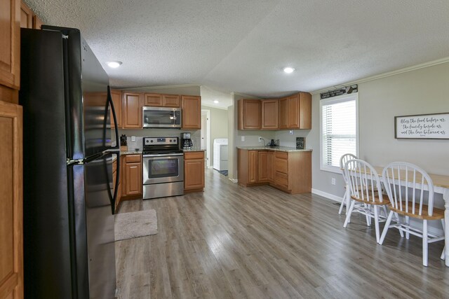 269 Moore Ln, Blue Eye, MO 65611 - kitchen featuring appliances with stainless steel finishes, washer / dryer, light wood-style floors, a textured ceiling, and vaulted ceiling