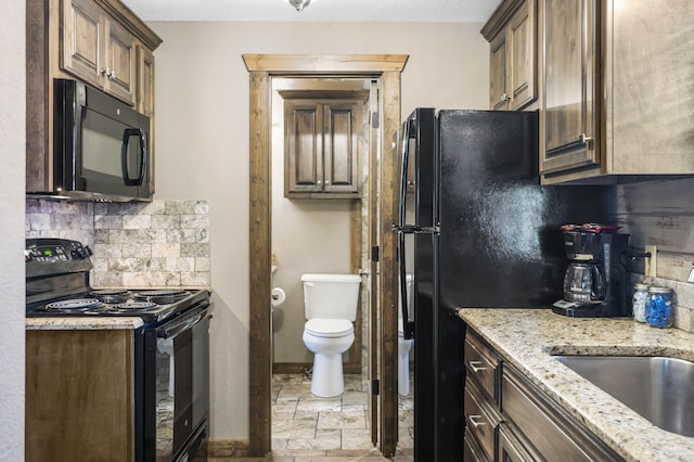 26 Cave Ln Unit 10, Indian Point, MO 65616 - kitchen featuring black appliances, a sink, tasteful backsplash, light stone counters, and baseboards