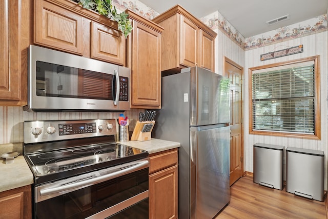 24 Village Trl Unit 13-2, Branson, MO 65616 - kitchen featuring appliances with stainless steel finishes, light countertops, light wood-style flooring, and wallpapered walls