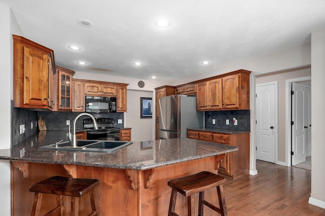 4353 S Frisco Trails Rd, Springfield, MO 65810 - kitchen featuring black appliances, a peninsula, dark wood-style floors, tasteful backsplash, and brown cabinets