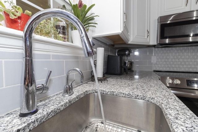150 Licaria Rd, Ozark, MO 65721 - kitchen view of stainless steel appliances, decorative backsplash, white cabinets, and light stone countertops