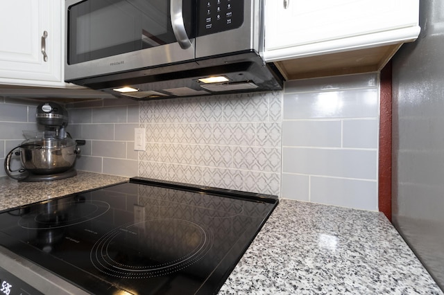 150 Licaria Rd, Ozark, MO 65721 - kitchen view of stainless steel microwave, white cabinets, tasteful backsplash, range, and light stone countertops