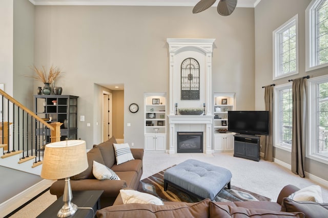 3262 S Thornridge Dr, Springfield, MO 65809 - living room with a towering ceiling, a tiled fireplace, ceiling fan, stairs, and baseboards