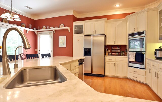 607 Sumac Ln, Marshfield, MO 65706 - kitchen with appliances with stainless steel finishes, a sink, light wood-style floors, hanging light fixtures, and white cabinetry