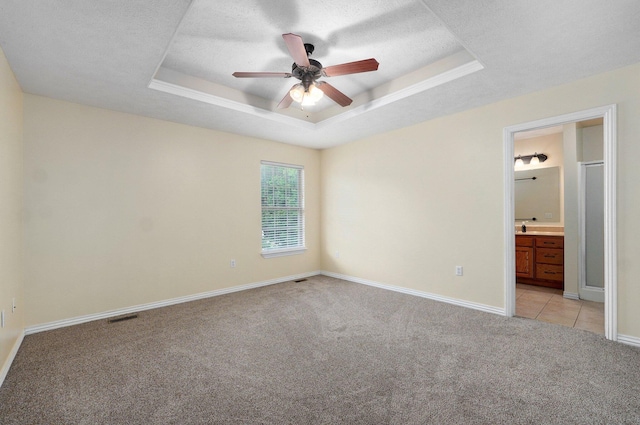 259 Aven Ave, Sparta, MO 65753 - unfurnished bedroom featuring light carpet, a tray ceiling, a textured ceiling, ensuite bathroom, and a ceiling fan