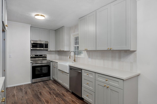 2411 S Rogers Ave, Springfield, MO 65804 - kitchen featuring appliances with stainless steel finishes, a sink, tasteful backsplash, dark wood finished floors, and light countertops