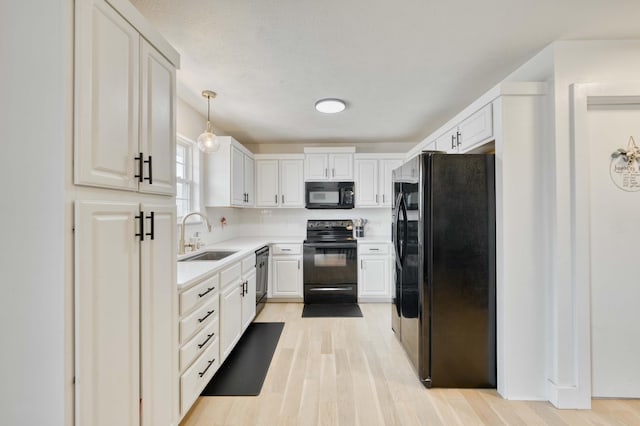 317 Cinnamon Ct, Sparta, MO 65753 - kitchen with black appliances, a sink, light wood finished floors, light countertops, and white cabinetry