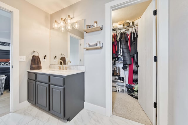 317 Cinnamon Ct, Sparta, MO 65753 - bathroom featuring vanity, a walk in closet, baseboards, and marble look tiles