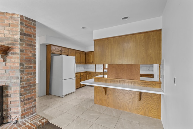 824 Highland Dr, Aurora, MO 65605 - kitchen featuring freestanding refrigerator, brown cabinets, light countertops, a peninsula, and a breakfast bar