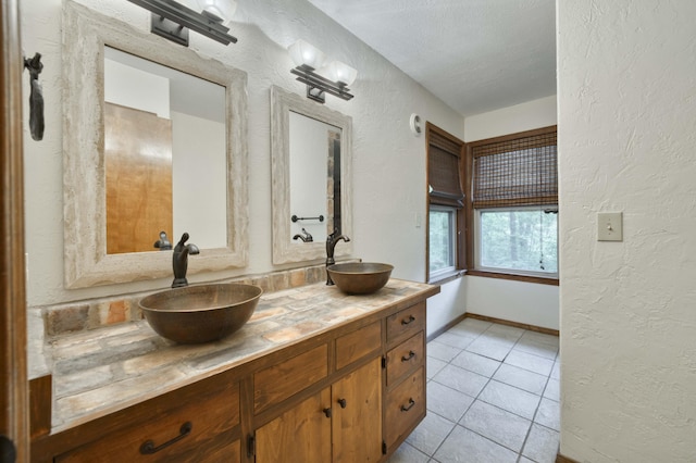 224 Loveland Dr, Rogersville, MO 65742 - full bath with a textured wall, double vanity, tile patterned floors, baseboards, and a textured ceiling