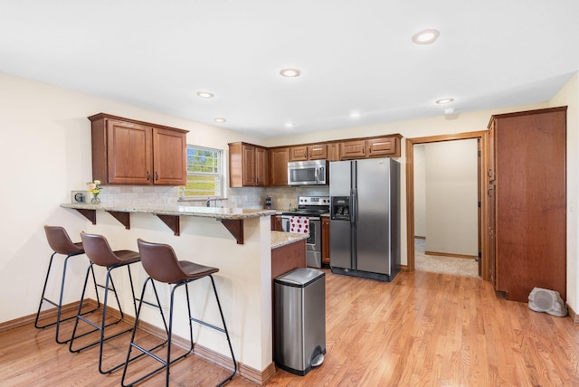 6755 W Farm Rd Unit 194, Republic, MO 65738 - kitchen featuring appliances with stainless steel finishes, a peninsula, a kitchen breakfast bar, decorative backsplash, and light stone counters