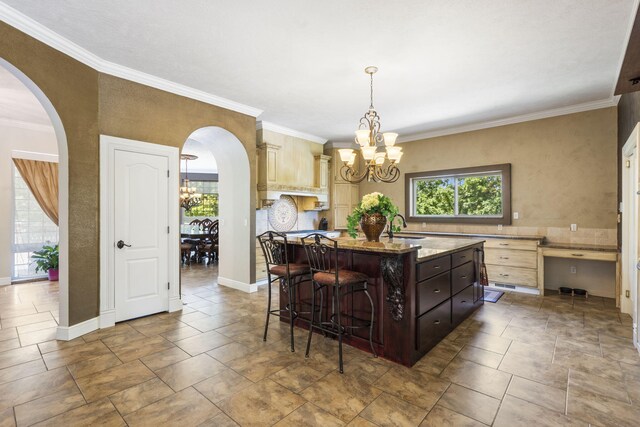 200 Barnes Ln, Branson, MO 65616 - kitchen featuring a chandelier, a breakfast bar area, arched walkways, a kitchen island with sink, and light stone counters