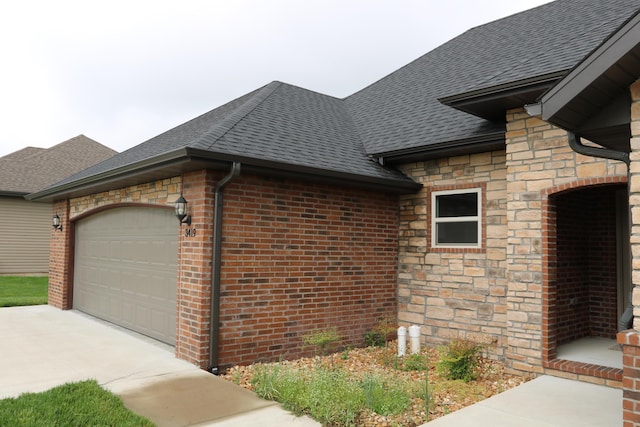 3419 S Suburban Ave, Springfield, MO 65807 - view of side of home featuring stone siding, concrete driveway, roof with shingles, and an attached garage