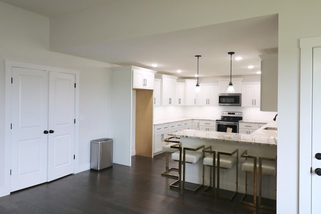 3419 S Suburban Ave, Springfield, MO 65807 - kitchen featuring stainless steel appliances, a peninsula, dark wood finished floors, light stone countertops, and recessed lighting