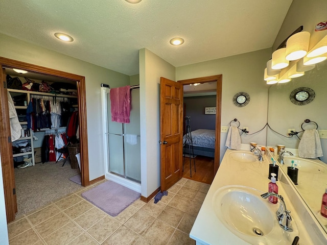 1054 W Itaska Rd, Nixa, MO 65714 - ensuite bathroom featuring a shower stall, double vanity, a walk in closet, tile patterned floors, and a textured ceiling