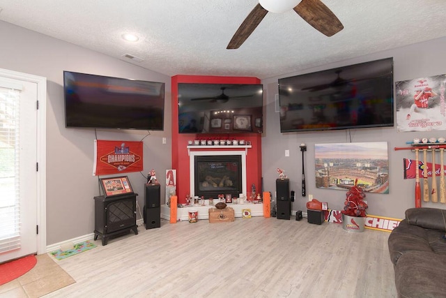 1054 W Itaska Rd, Nixa, MO 65714 - living area with a ceiling fan, wood finished floors, a glass covered fireplace, a textured ceiling, and plenty of natural light