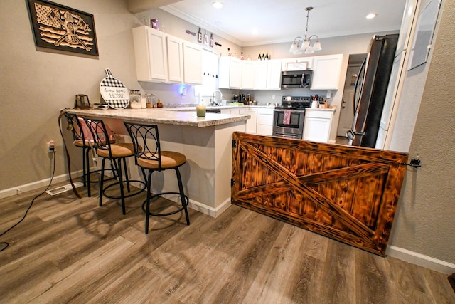 511 C St, Deepwater, MO 64740 - kitchen with stainless steel appliances, a peninsula, white cabinets, ornamental molding, and a chandelier