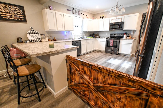 511 C St, Deepwater, MO 64740 - kitchen featuring stainless steel appliances, a peninsula, a sink, wood finished floors, and a chandelier