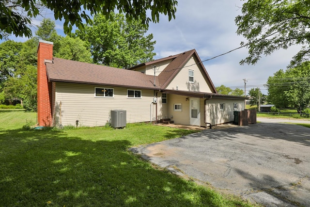 1104 E Buffalo St, Bolivar, MO 65613 - rear view of property featuring central AC unit, a chimney, a shingled roof, and asphalt driveway