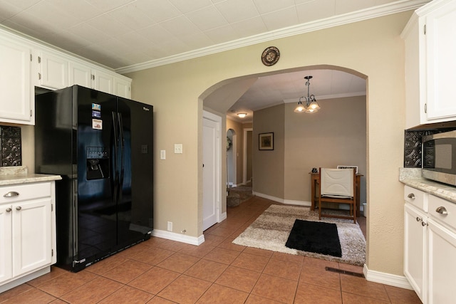 1104 E Buffalo St, Bolivar, MO 65613 - kitchen featuring black fridge, crown molding, arched walkways, white cabinets, and light tile patterned floors