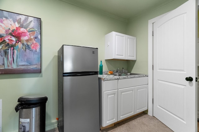 36205 State Highway 413, Crane, MO 65633 - kitchen featuring freestanding refrigerator, crown molding, white cabinetry, a sink, and light colored carpet