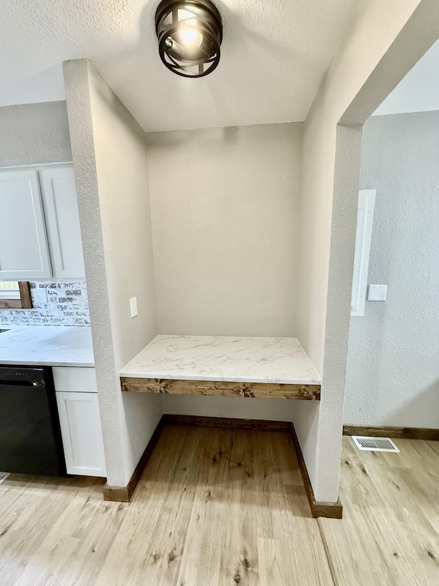 8030 Indiana Dr, Houston, MO 65483 - detailed view of black dishwasher, wood finished floors, baseboards, a textured wall, and a textured ceiling