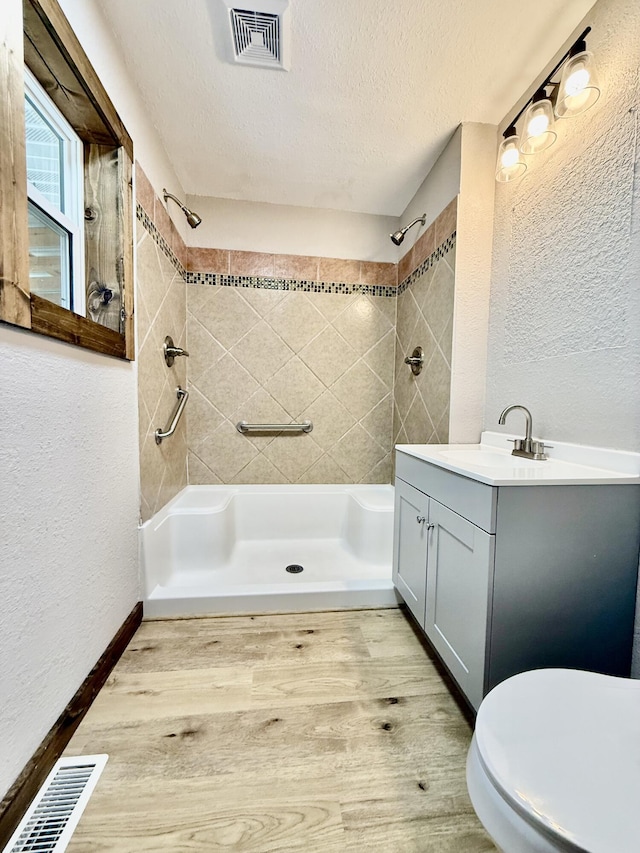 8030 Indiana Dr, Houston, MO 65483 - bathroom with a textured wall, toilet, vanity, a tile shower, and a textured ceiling