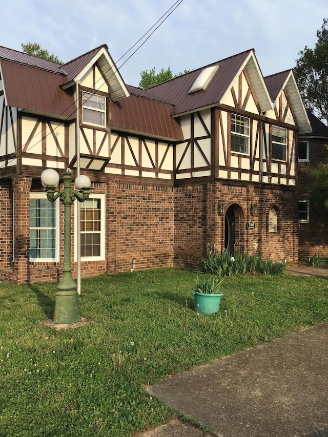 310 S 6th St, Thayer, MO 65791 - tudor home with brick siding, a front yard, and metal roof