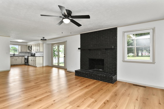 2658 S Hillsboro, Springfield, MO 65802 - unfurnished living room with a sink, light wood-style flooring, a ceiling fan, baseboards, and a textured ceiling