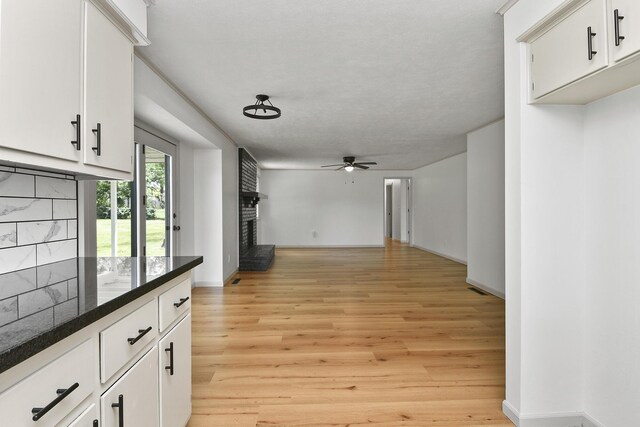 2658 S Hillsboro, Springfield, MO 65802 - unfurnished living room with a fireplace, a ceiling fan, light wood-style flooring, and baseboards