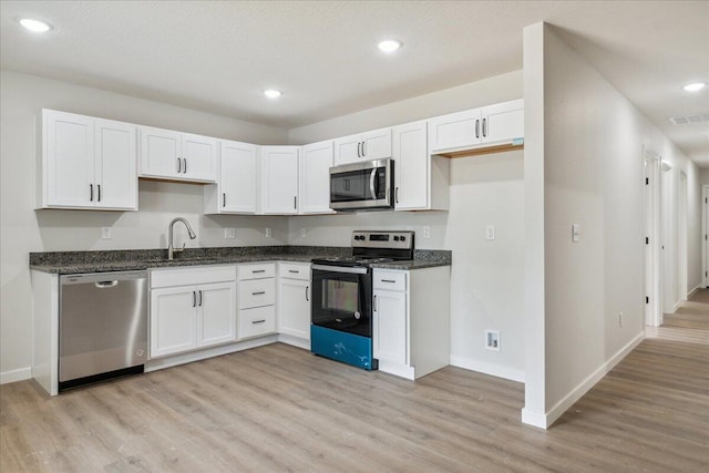 1052 S Overhill Ave, Springfield, MO 65802 - kitchen featuring appliances with stainless steel finishes, light wood finished floors, a sink, white cabinets, and baseboards
