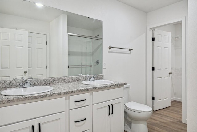 1052 S Overhill Ave, Springfield, MO 65802 - full bathroom with a stall shower, double vanity, wood finished floors, a walk in closet, and toilet