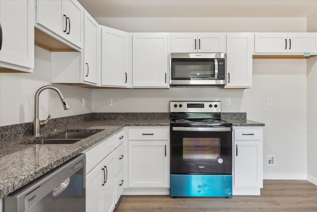 1052 S Overhill Ave, Springfield, MO 65802 - kitchen featuring stainless steel appliances, a sink, light wood-style flooring, and dark stone countertops