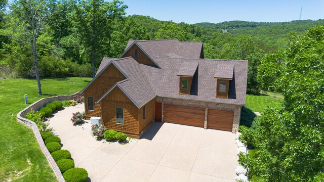 184 Appaloosa Trl, Saddlebrooke, MO 65630 - view of front of property featuring a garage, concrete driveway, a view of trees, and a shingled roof