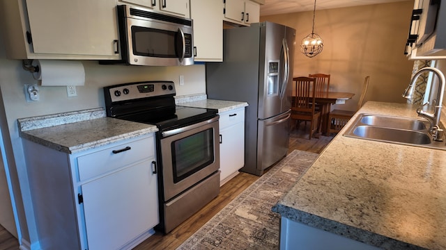 606 W Clover Dr, Clinton, MO 64735 - kitchen featuring appliances with stainless steel finishes, a sink, a chandelier, and dark wood-type flooring
